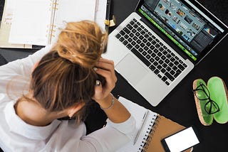 Person with head in their hands sitting at a laptop