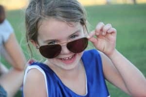 Young girl with oversized sun glasses, laughing.