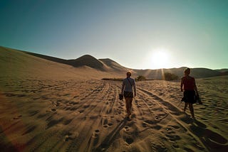 Two people walking in the sand dunes