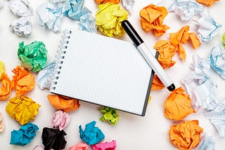 Office workspace with an empty notebook, crumpled paper