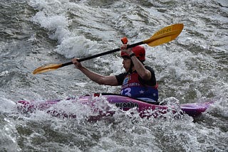 The author whitewater kayaking in a slalom race