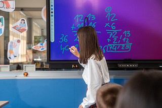 Photo of a woman teaching math to a class of kids.