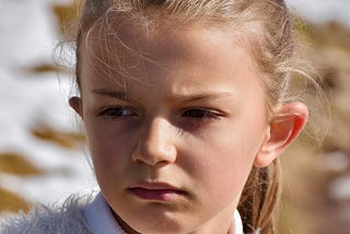 Young girl in white sweater looking angry and upset