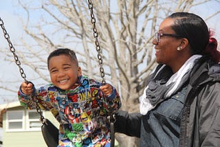 mother pushing child on swing