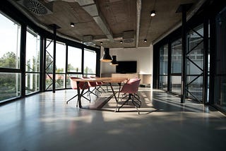 Large conference room full of natural light, with a table and mauve chairs