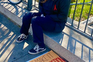 teen girl sits outside the Tennessee State Capitol in Nashville with a sign that reads “Will I make it to my own graduation?” in the wake of the Nashville school shooting