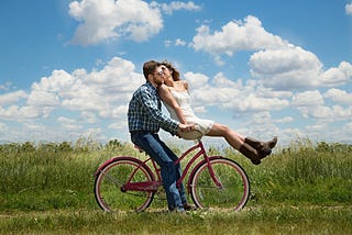 A Man Sitting On His Bicycle Holding His Partner