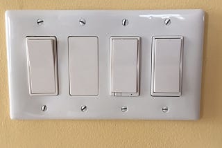 a set of four light switches in a single panel (4-gang box)