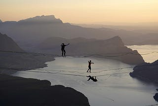 Two people walk over a tight rope, symbolizing the fine line between giving mindfully and overgiving