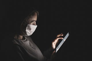 Picture of a woman wearing a mask and using a phone