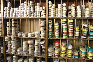 Shelves in a shoe shop, subdivided into sections, all containing espadrilles in a range of different colours