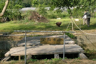 Two men walk around the yard outside of the Hong Kong Vipassana center, A sign reads in English and Chinese “student area ends here”