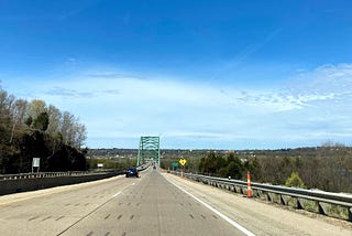 A car drives on a highway towards a covered bridge.