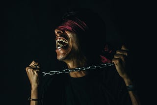 Main blindfolded and in chains screaming as he fights the chains of quiet desperation