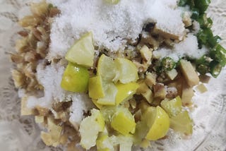 Glass bowl with cubes of ginger, cut pieces of green chillies, cut pieces of lemons, and salt. Add the lemon juice and mix, and the pickle is ready!