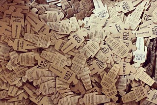 A cardboard box full of tiny trumps: 3" tall cardboard cutout stickers in the silhouette of President Trump, with protest slogans written on the front and instructions on the back