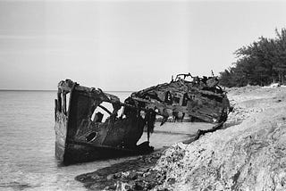 Black and white photo of an old shipwreck on a beach