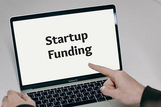 Finger pointing at laptop screen that reads “Startup Funding”