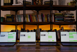Four laptops on a table in front of a bookcase running machine learning speed tests on their screen
