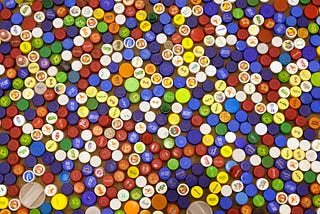 A view from above of a large quantity of bottle caps of different colors places very close to each other