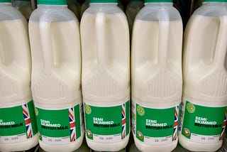 A row of 2 pint semi skimmed milk bottles in a fridge