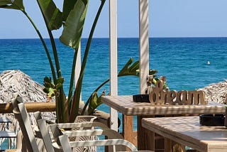 Furniture set by the sea with the wooden word “dream” placed on a table.