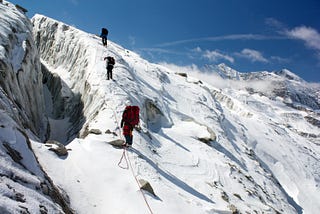 Hikers climbing up snowy mountain