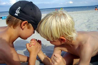 Two boys arm wrestling at the beach. Seyi Akinsanya: Business Supplier and Buyer Power in Investing. Business, Investing, Porter