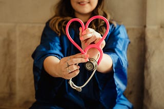 Healthcare provider with heart-shaped stethoscope.