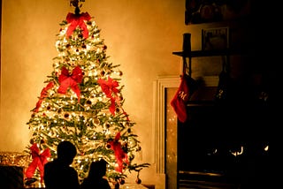 Children seated in front of glowing Christmas tree