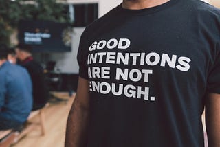 Man wearing a t-shirt bearing the inscription “Good intentions are not enough.”