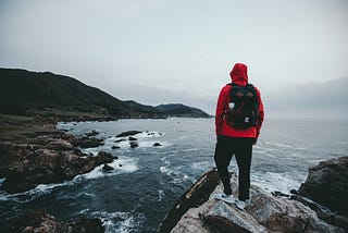 7 Powerful Life Lessons From Living Out of 2 Backpacks For Years — man with red jacket standing on lake