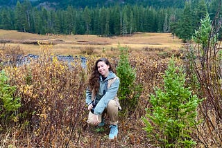 The author kneeling in a meadow with her film camera in Yellowstone National Park