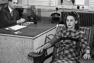 Black and white photo from the 1950s illustrating a woman with a distant stare while taking a polygraph/ lie detector test.