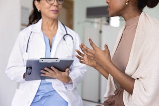 Una persona adulta hablando con un médico en una cita.