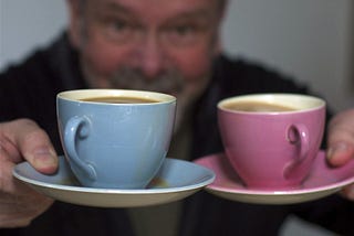 Man holding out two cups of coffee
