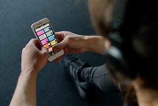 Man with headphones holds smartphone open to Spotify landing page