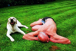 A man and his dog lying on the grass.