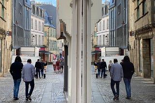 Two men walking down a street, reflected in a shop window