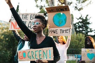a young climate change activist in nice black shirt with a placard saying “Go Green”
