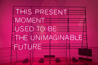 THIS PRESENT MOMENT USED TO BE THE UNIMAGINABLE FUTURE — in hot pink flourescent lights