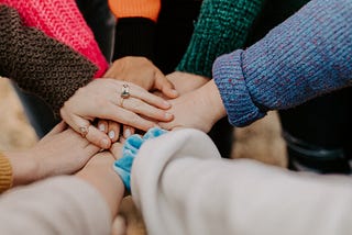 A group of people bringing their hands together, signifying unity