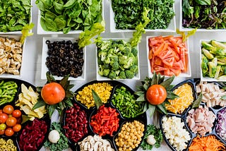 colorful salad bar with a wide variety of vegetables, meats, and cheeses