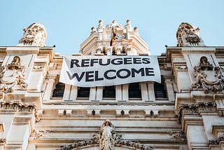Picture of a banner hanging from a building with the words: Refugees Welcome