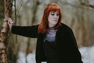 Woman beside a tree looking nonplussed. Not caring what others think is hard.