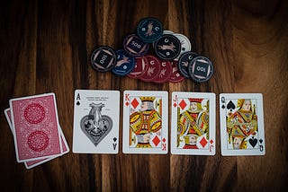 a pile of casino chips and four cards that almost make up a royal flush