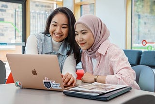 two females sitting looking at a laptop together