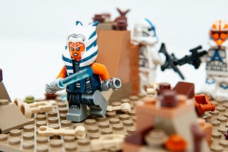Lego figure of Star Wars character Ahsoka Tano holding a lightsaber and running.