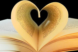 An image of an open book with two pages joined together to form a heart.