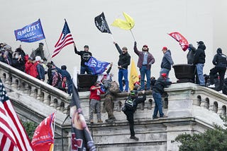 A picture showing January 6th insurrectionists climbing on the railings at the capitol building.